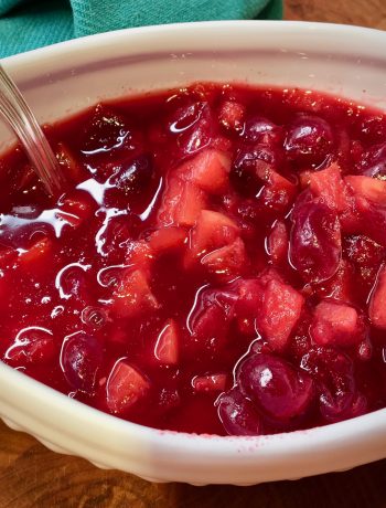 cranberry sauce with apples in a white dish with a silver spoon