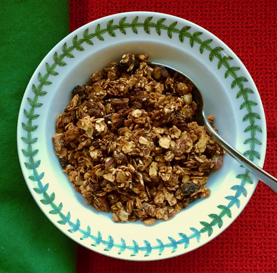 granola in a white bowl rimmed with green on a green and red cloth
