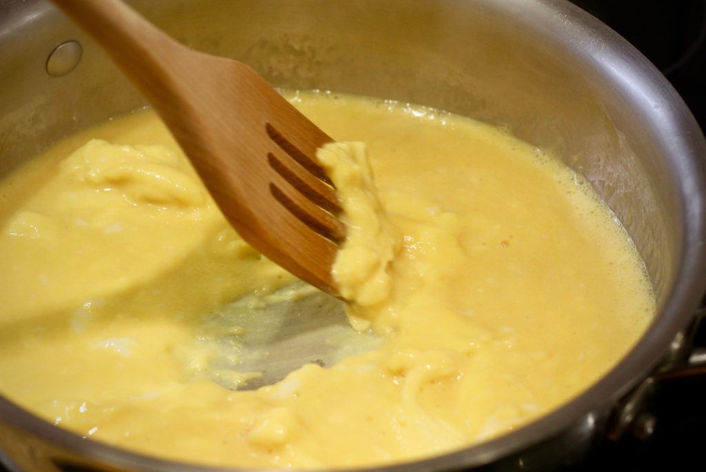 eggs in a stainless steel pan with wood stirrer