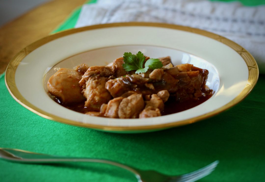 chicken thighs with caramel sauce in white bowl on green placemat with white napkin