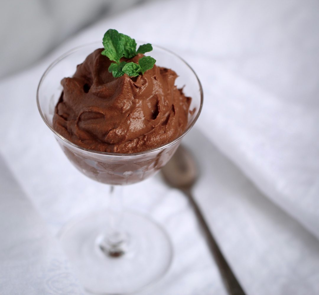 sweet potato chocolate mousse garnished with fresh mint in an aperatif glass on a whilte cloth