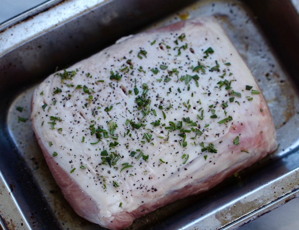 raw pork loin sprinkled with salt, pepper and chopped fresh rosemary ina metal roasting pan