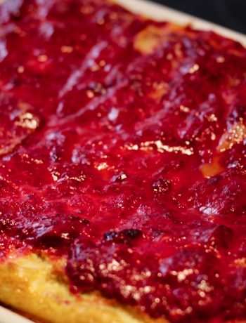 baked raspberry french toast in a ceramic baking dish on a black surface