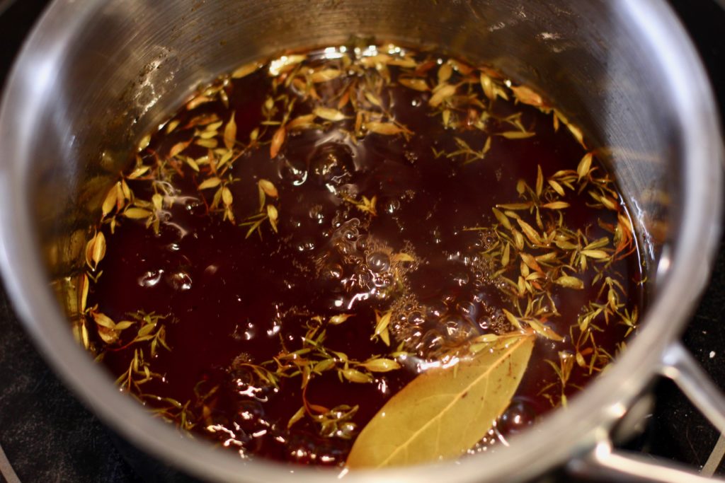 apple cider glaze boiling in a small stainless steel pan
