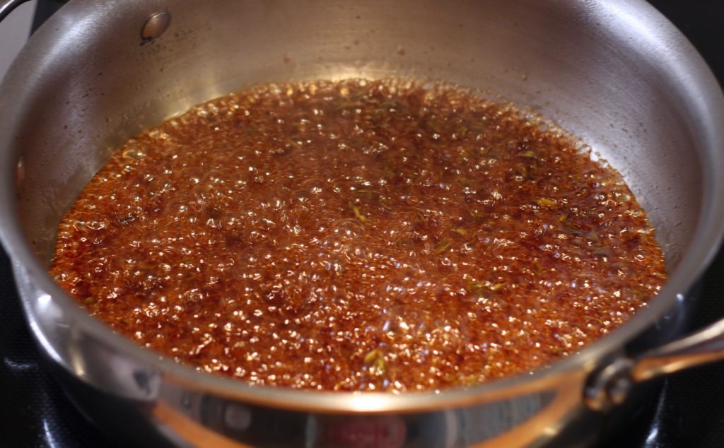 apple cider vinegar glaze bubbling in a stainless steel pan