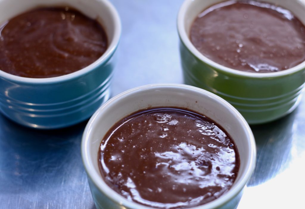 dairy=-free chocolate pudding in three ramekins on a stainless steel surface