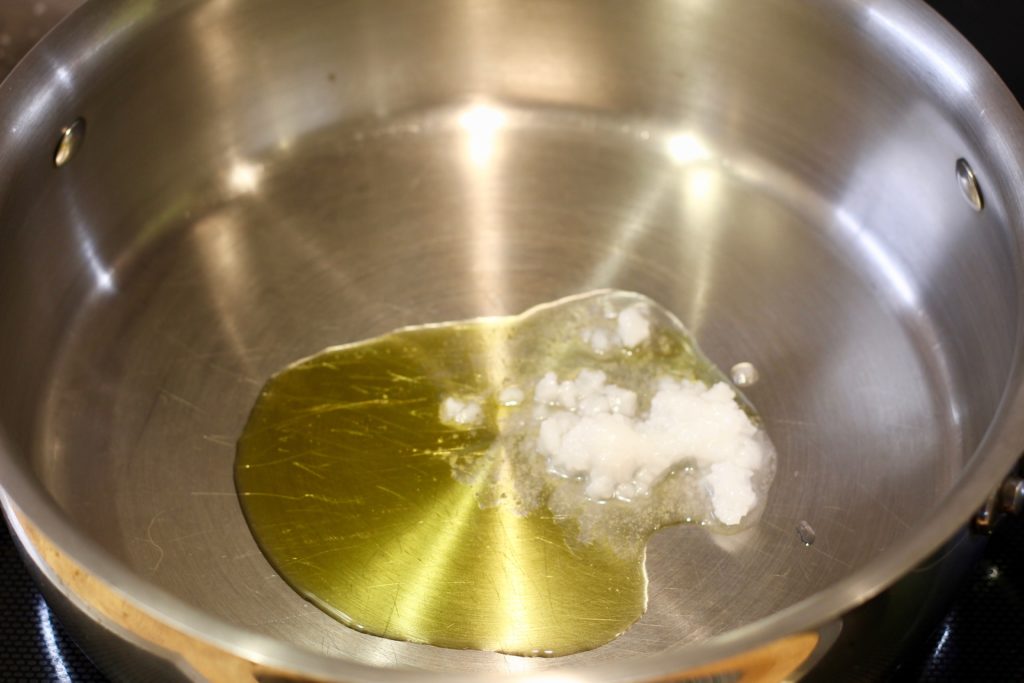 olive and coconut oils heating in a stainless steel pan