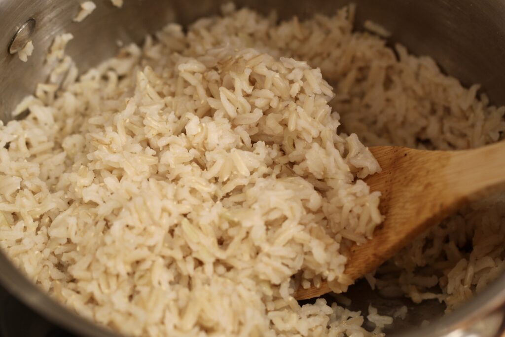 brown rice in a pan with a wooden spoon