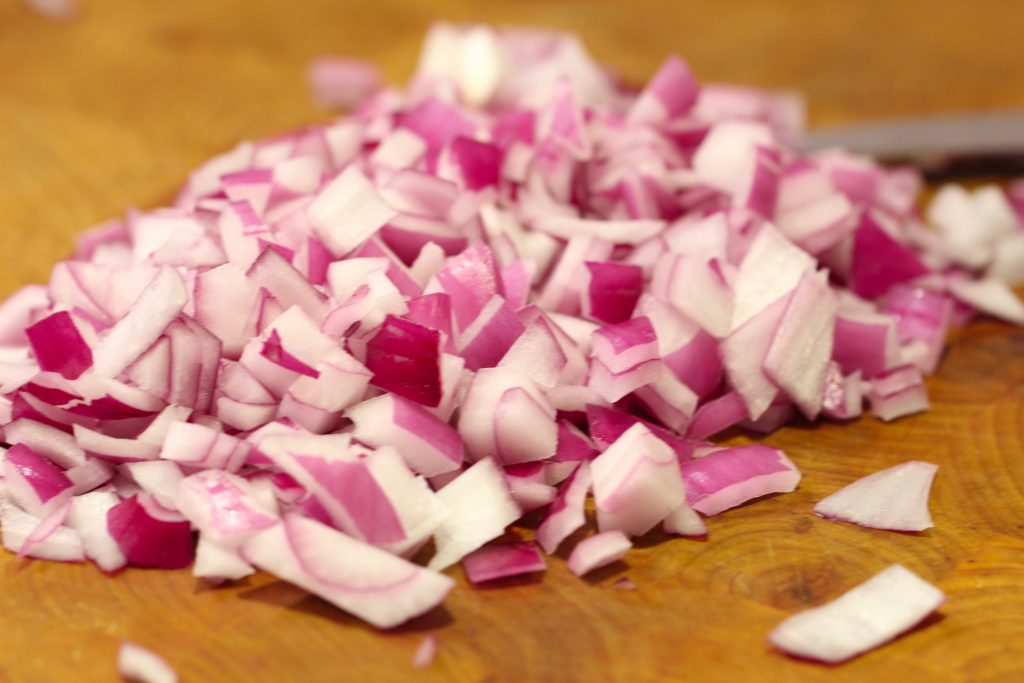 chopped red onions on a wood cutting board