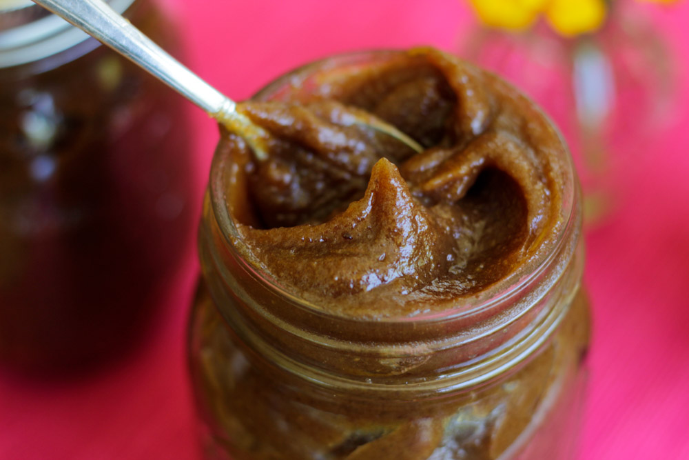 date paste in a mason jar with a silver spoon on a red cloth