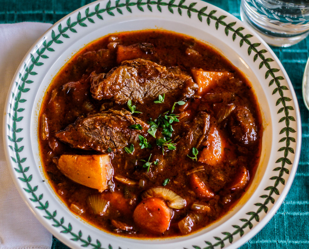pot roast in a white bowl on a green cloth with a white napkin