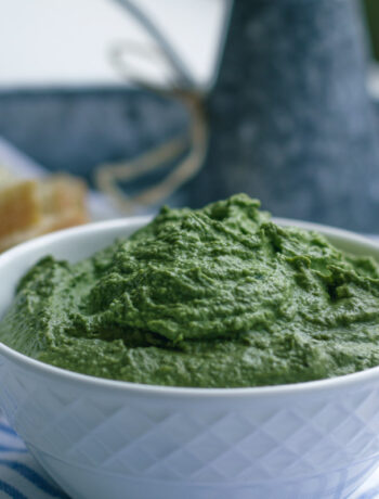 vegan pesto sauce in a white bowl on a blue and white cloth