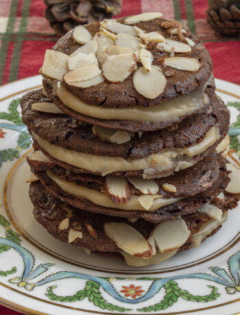stack of sandwich cookies on white plate on red cloth