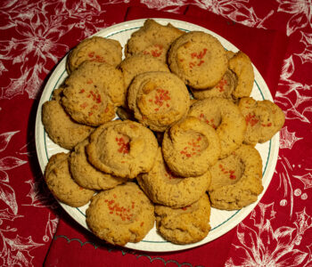 almond spritz cookies on a white plate on a red tablecloth