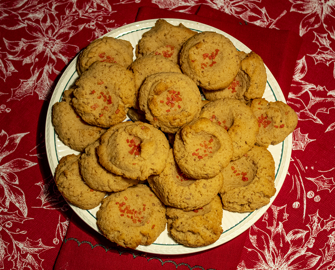 almond spritz cookies on a white plate on a red tablecloth